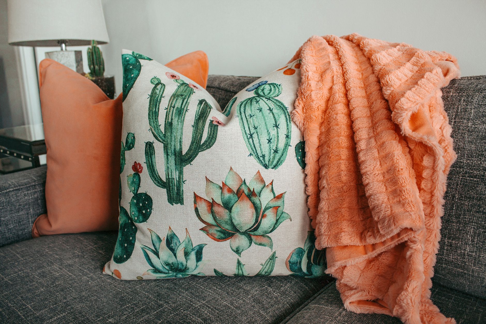 A living room styled with a grey sofa and cactus-print cushions